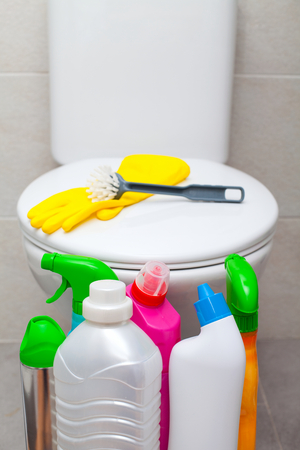 Colorful bathroom cleaning products and yellow rubber gloves, white lavatory pan in the backgroundの写真素材