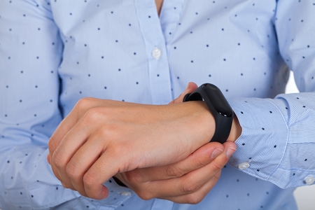 Close up picture of young female wearing mi fit band, checking her pluse & steps for the dayの写真素材