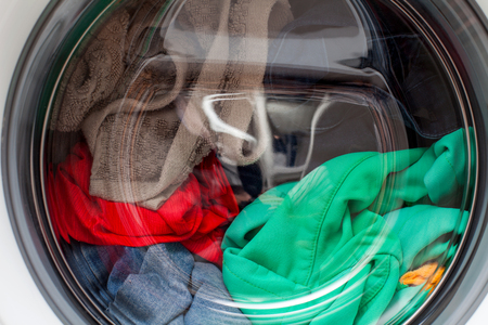 Modern automatic washing machine loaded with colorful clothesの写真素材