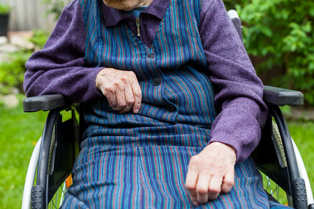 Disabled senior woman sitting in wheelchair outdoorの写真素材