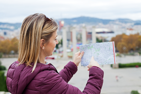 Charming female tourist searching for the right direction in the city map in Barcelona, Cataloniaの写真素材
