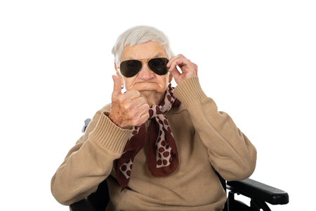Blind elderly lady sitting in a wheelchair on isolated backgroundの写真素材