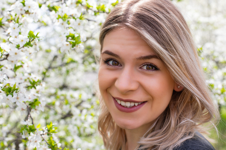 Portrait of an attractive young woman outdoor in blooming garden, springtime