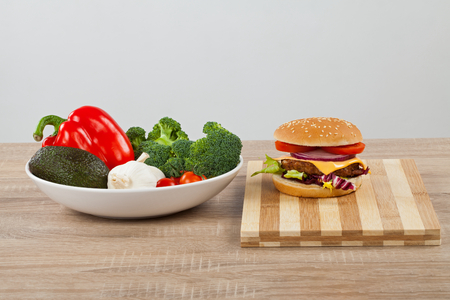 Delicious cheeseburger and salad on a wooden cutting boardの写真素材