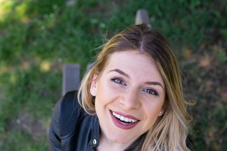 Top view portrait of a beautiful charming woman spending time outdoor, smiling to the cameraの写真素材