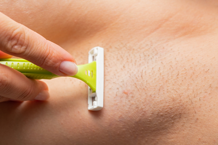 Close up picture of hairy armpit, woman shaving with razorの写真素材
