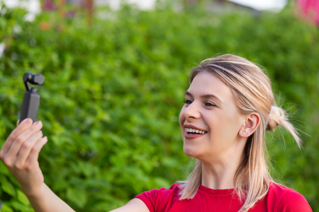Young beautiful woman holding DJI Osmo Camera, ideal device for travel videos and photosの写真素材
