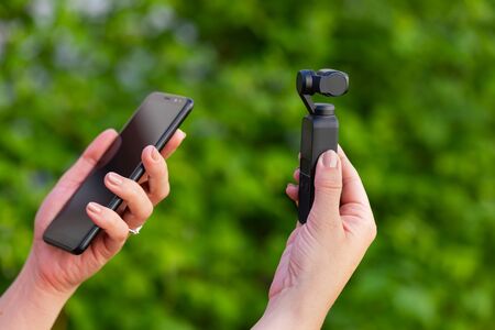 Close up picture of osmo videographer and smart phone in female hands, green backgroundの写真素材