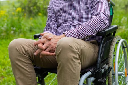 Picture of an elderly man  sitting in a wheelchair spending time outdoor in the parkの写真素材