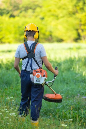 Young gardener cutting the grass with a petrol lawn mower