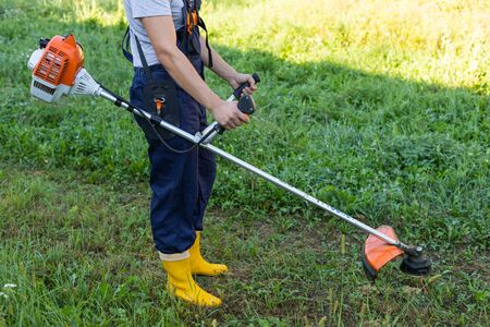 Young gardener cutting the grass with a petrol lawn mower