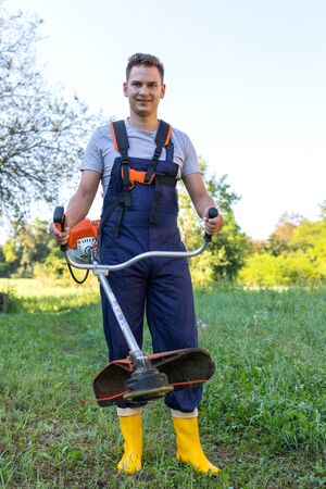 Young gardener cutting the grass with a petrol lawn mowerの写真素材