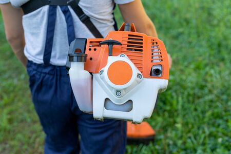 Young gardener cutting the grass with a petrol lawn mower