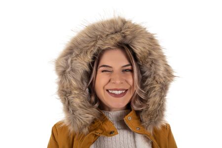 Portrait of charming young woman wearing mustard parka jacket with furry hood, smiling to the camera on isolatedの写真素材