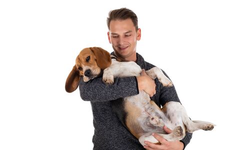 Young man holding a tri colored adorable beagle on isolated backgroundの写真素材