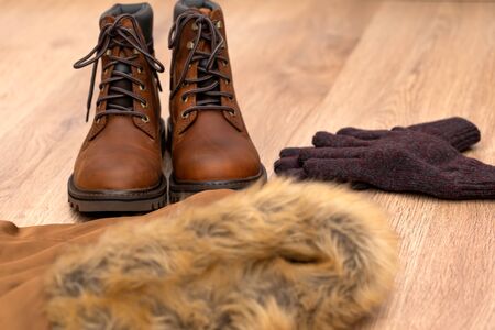 Warm winter clothes, mens boot, coat and gloves on wooden floorの写真素材