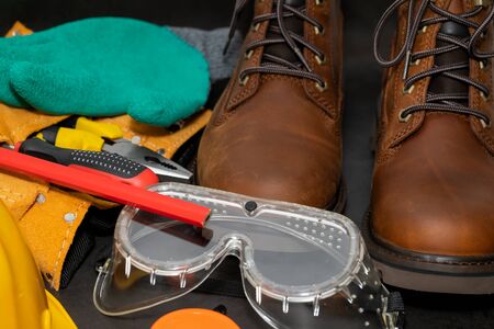 Safety gloves, boots , yellow hard hat on a black backgroundの写真素材
