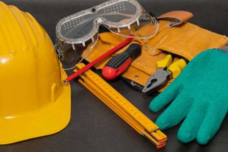 Safety gloves, boots , yellow hard hat on a black background