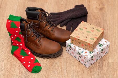 Warm winter clothes, mens boots, gloves and gift box on wooden floorの写真素材