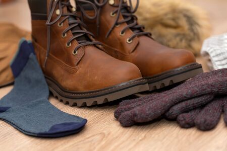 Warm winter clothes, mens boot, coat and gloves on wooden floorの写真素材