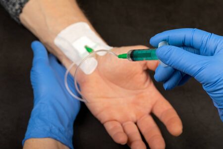 Doctor with blue gloves injecting medicine in a  vein catheter