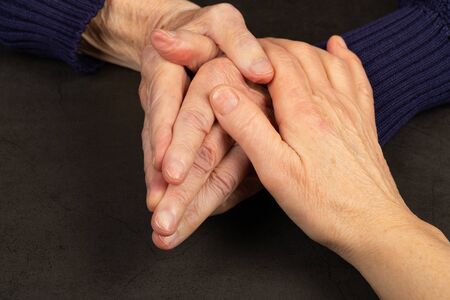 Caregiver touching elderly patients hand at home