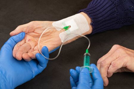 Doctor with blue gloves injecting medicine in a  vein catheter