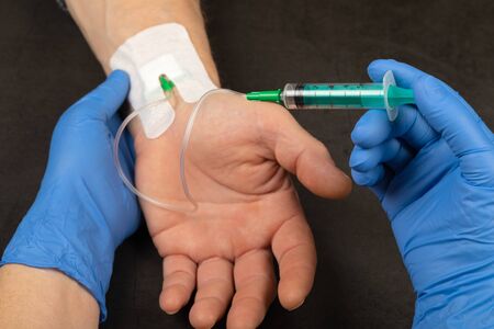 Doctor with blue gloves injecting medicine in a  vein catheter