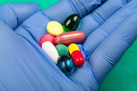 Close up picture of multi-colored medical drugs and vitamins in doctor's hand