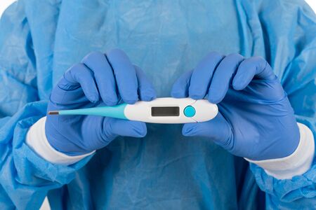 Close up picture of surgeon in blue protective uniform holding digital thermometer in hands