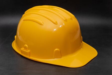 Professional yellow hard hat on dark background. Safety at work conceptの写真素材