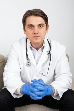 Portrait of a young male physician sitting on the couch in the officeの写真素材