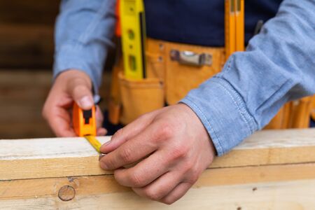 Close up picture of carpenters hands measuring plank - DIY renovation at homeの写真素材
