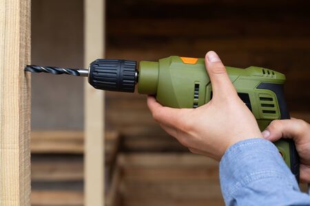 Close up picture of construction worker holding electric drill, renovation at home