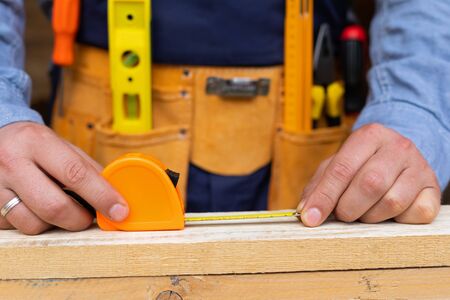 Close up picture of carpenters hands measuring plank - DIY renovation at homeの写真素材