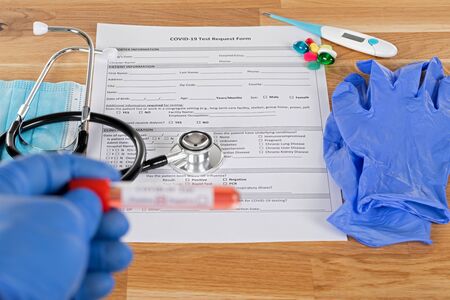 Close up picture of positive covid-19 blood test and medical supplies, treatment, mask and gloves on...
