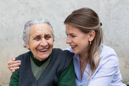 Young friendly woman embracing senior lady outdoor - quality time spent togetherの写真素材