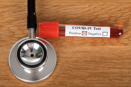 Positive Covid-19 blood test and stethoscope on wooden backgroundの写真素材