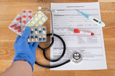 Close up picture of covid-19 blood test and medical supplies, pills on wooden backgroundの写真素材