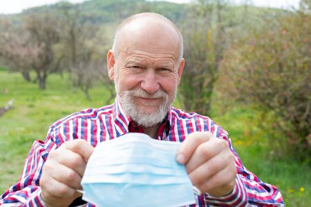 Portrait of elderly man with surgical mask spending time outdoors in the garden