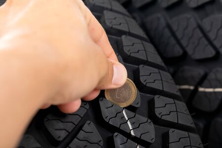 Close up picture of black new car tyre and mechanic's hand next to 