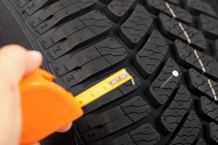 Close up picture of black new car tyre and mechanic's hand next to の写真素材