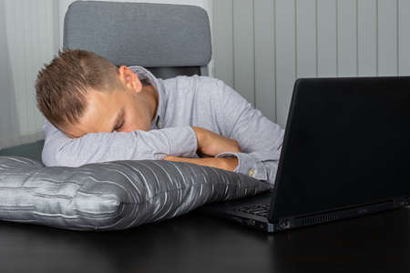 Tired young businessman sleeping at his desk