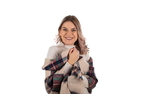 Cheerful woman wearing beige knitwear and warm scarf for winter days is posing on isolated backgroundの写真素材