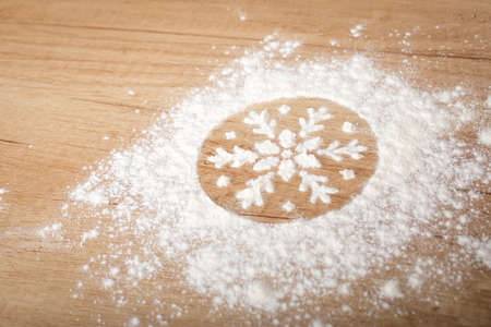 Picture of amazing snowflake made with flour, christmas baking utensils and ingredients on wooden tableの写真素材