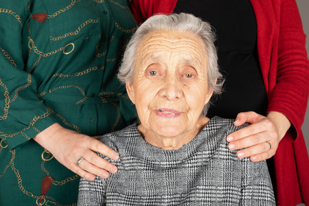 Close up portrait of happy grandmother with her daughters hands in the background