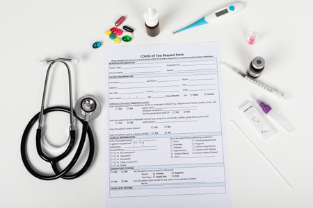 Close up picture of doctors hand holding coronavirus test and medical paperwork on white background