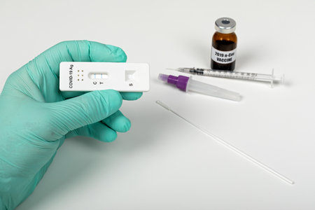 Close up picture of doctors hand holding coronavirus test and medical paperwork on white background