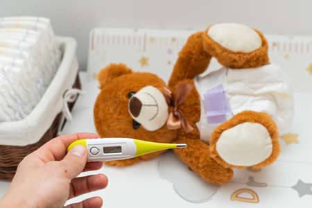 Brown teddy bear with diaper on  sitting in baby bedの写真素材