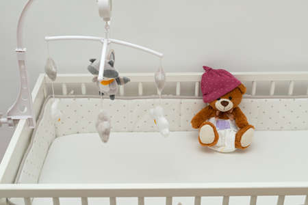 Pcture of a brown teddy bear with diaper on sitting in baby bed